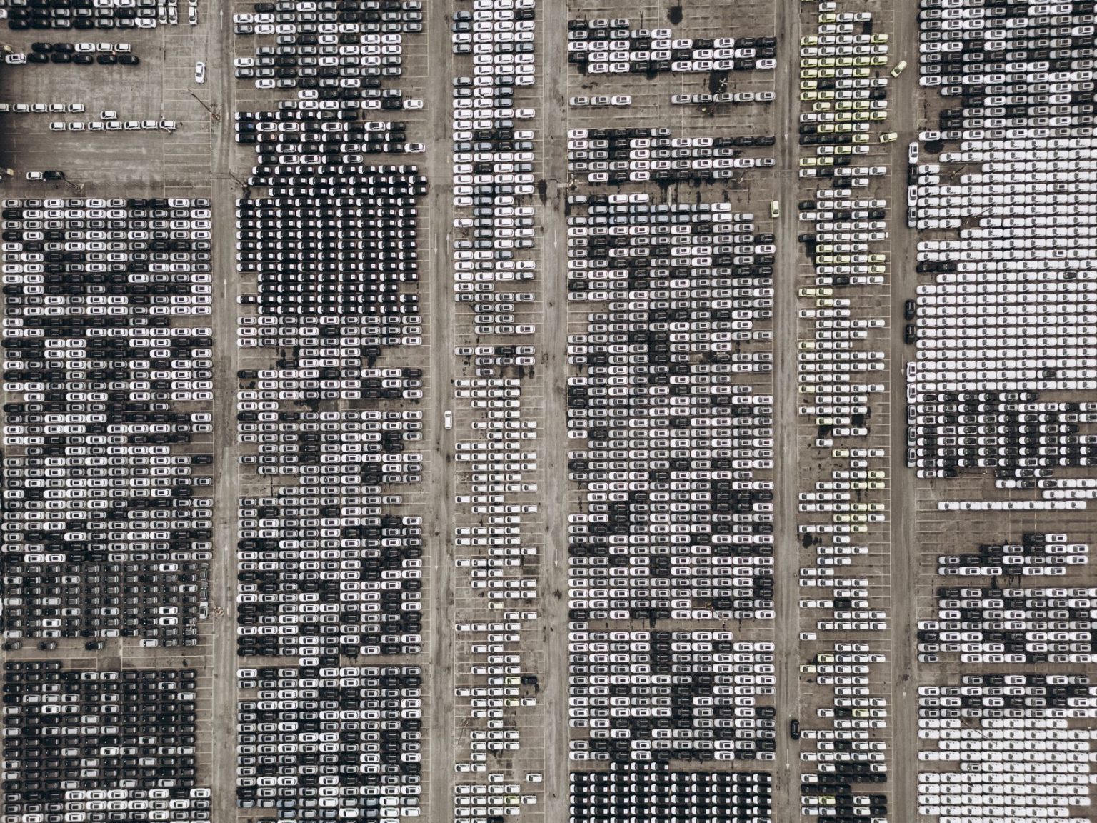 Vista aérea de um amplo estacionamento repleto de veículos novos no Brasil