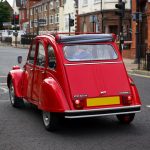 Citroën 2 CV clássico vermelho circulando por uma rua de Liverpool.