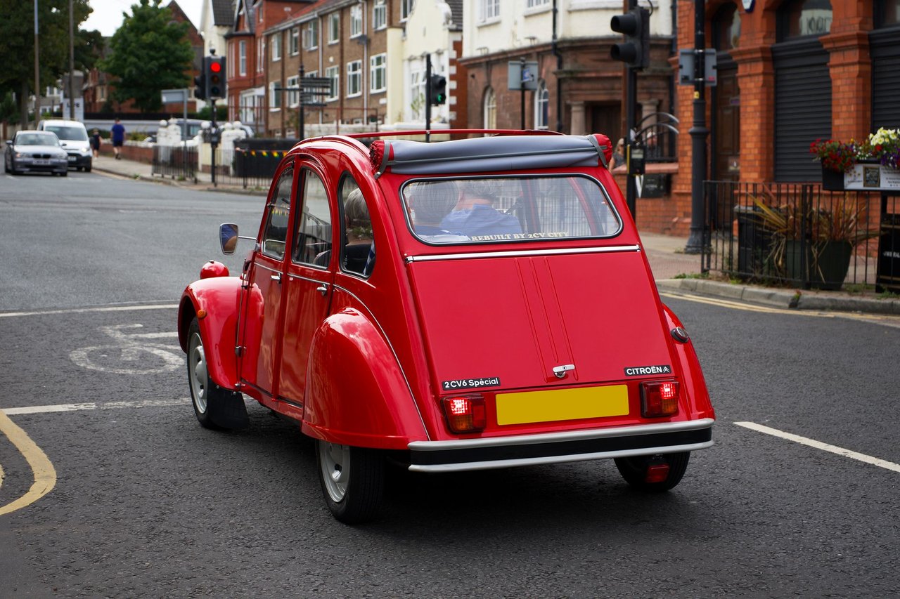 Citroën 2 CV clássico vermelho circulando por uma rua de Liverpool.