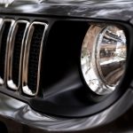 Detalhe da dianteira de um SUV Jeep preto, com destaque para a grade e o farol.