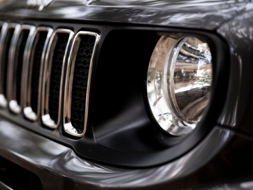 Detalhe da dianteira de um SUV Jeep preto, com destaque para a grade e o farol.