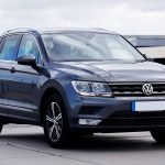 Volkswagen Tiguan cinza estacionado em um ambiente urbano, com prédios e vegetação ao fundo