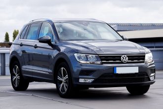 Volkswagen Tiguan cinza estacionado em um ambiente urbano, com prédios e vegetação ao fundo