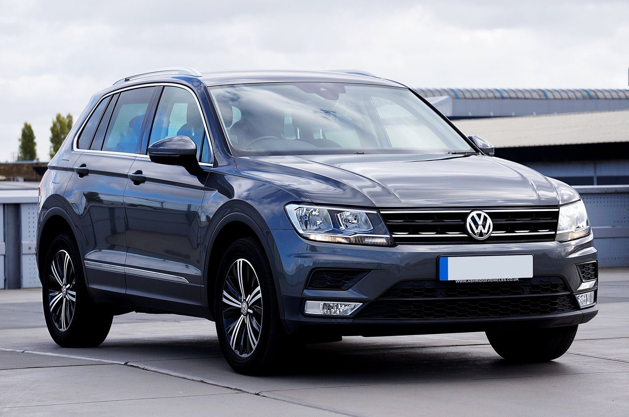 Volkswagen Tiguan cinza estacionado em um ambiente urbano, com prédios e vegetação ao fundo